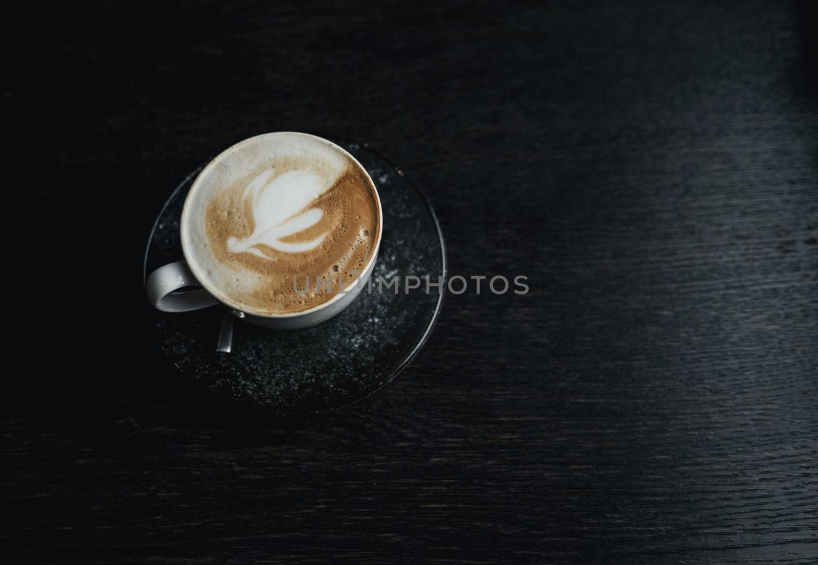 A cup of coffee with pattern in  cup on dark wooden background