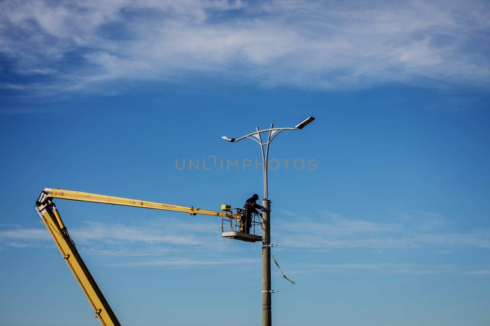 Street light repair works, worker repair street lamp at height, led lights replacement. 