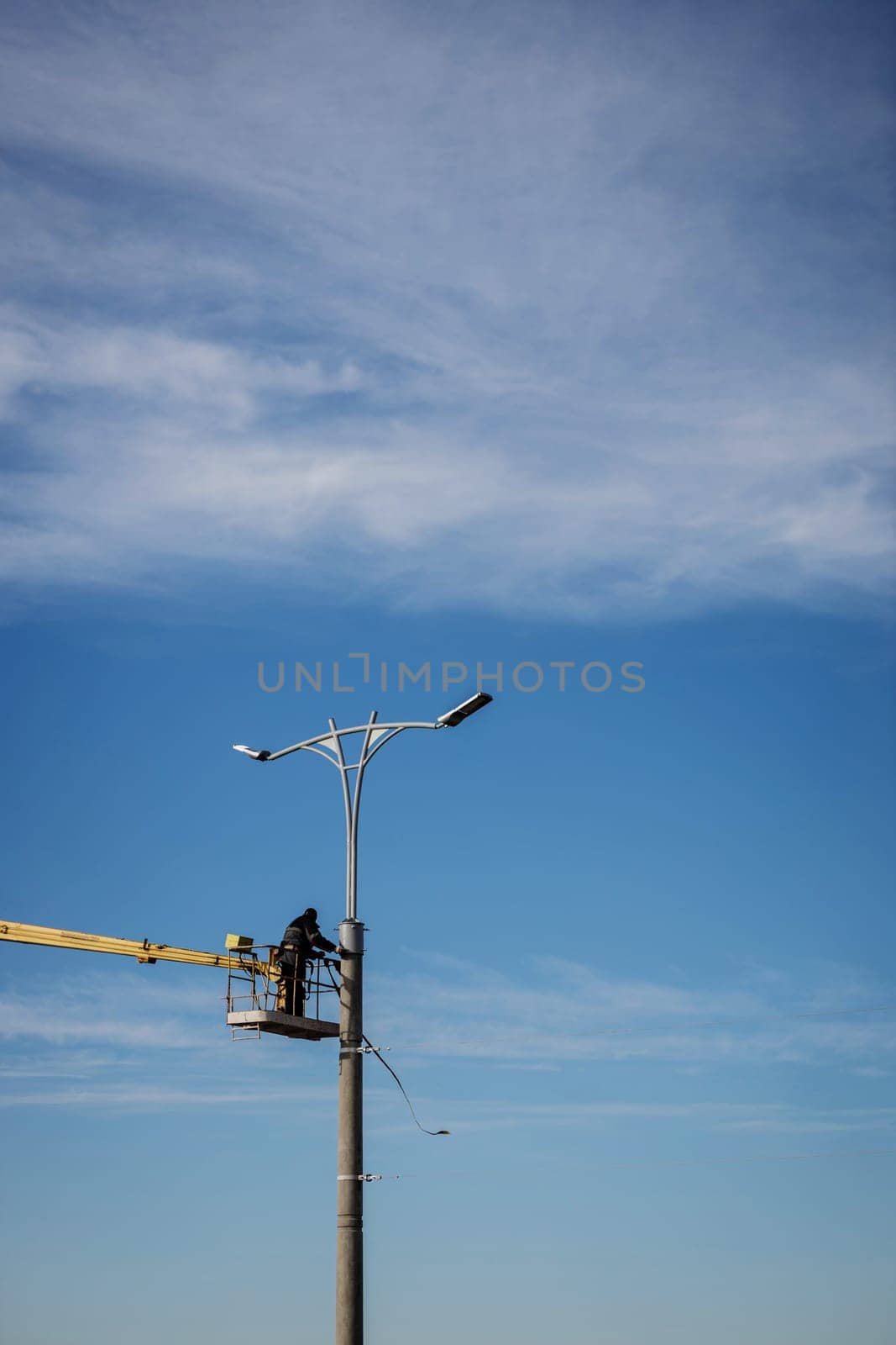 A worker in helmet is installing a new street lamp