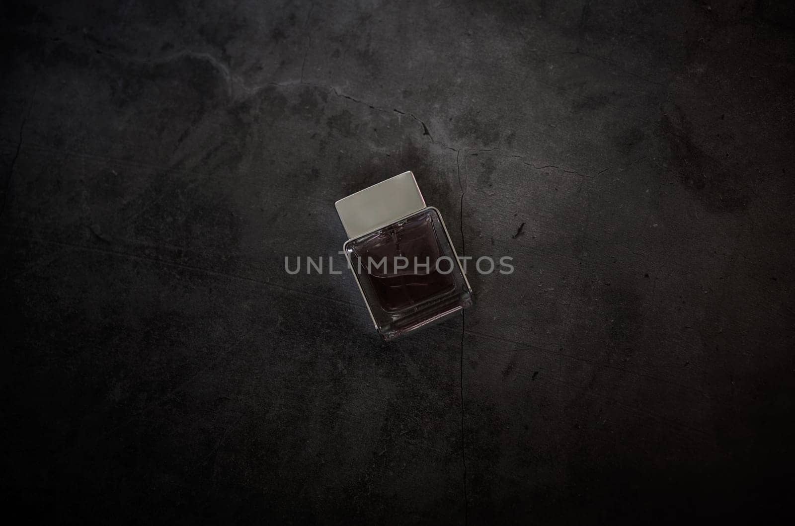 transparent fragrance perfume bottle on dark empty background. Top view. Horizontal. men's  cologne