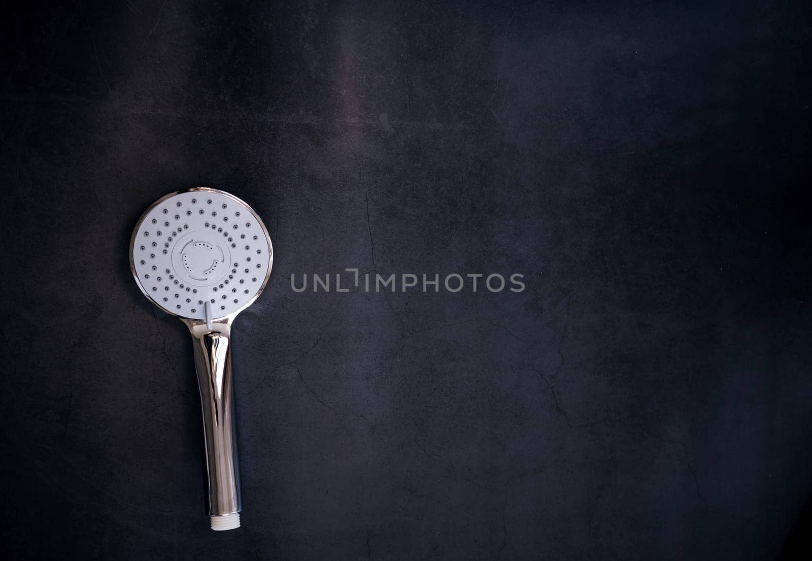 stainless steel shower head with the turn lever of a spray settings on a dark background. copy space