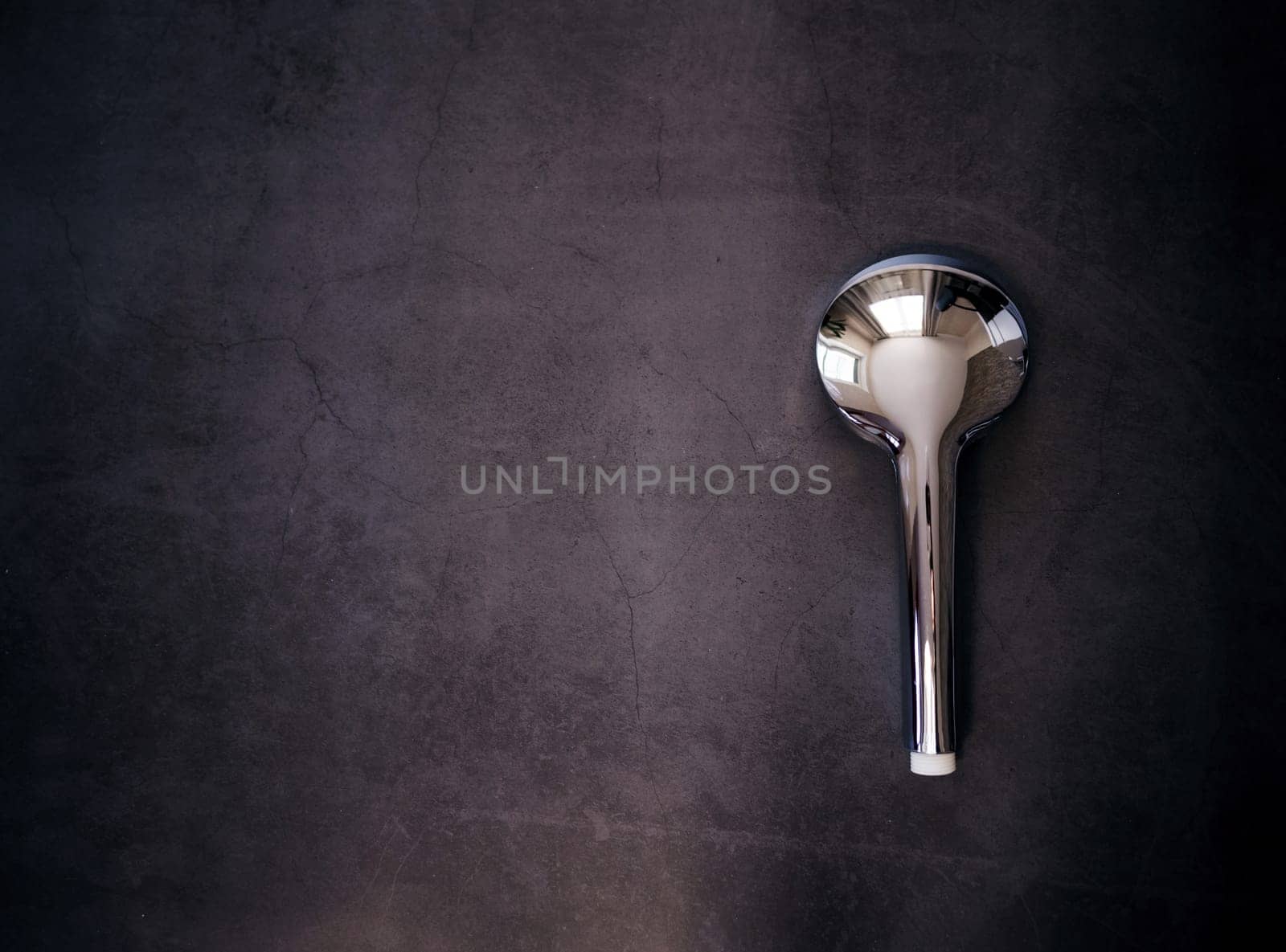 Silver stainless steel shower head on a dark background. copy space