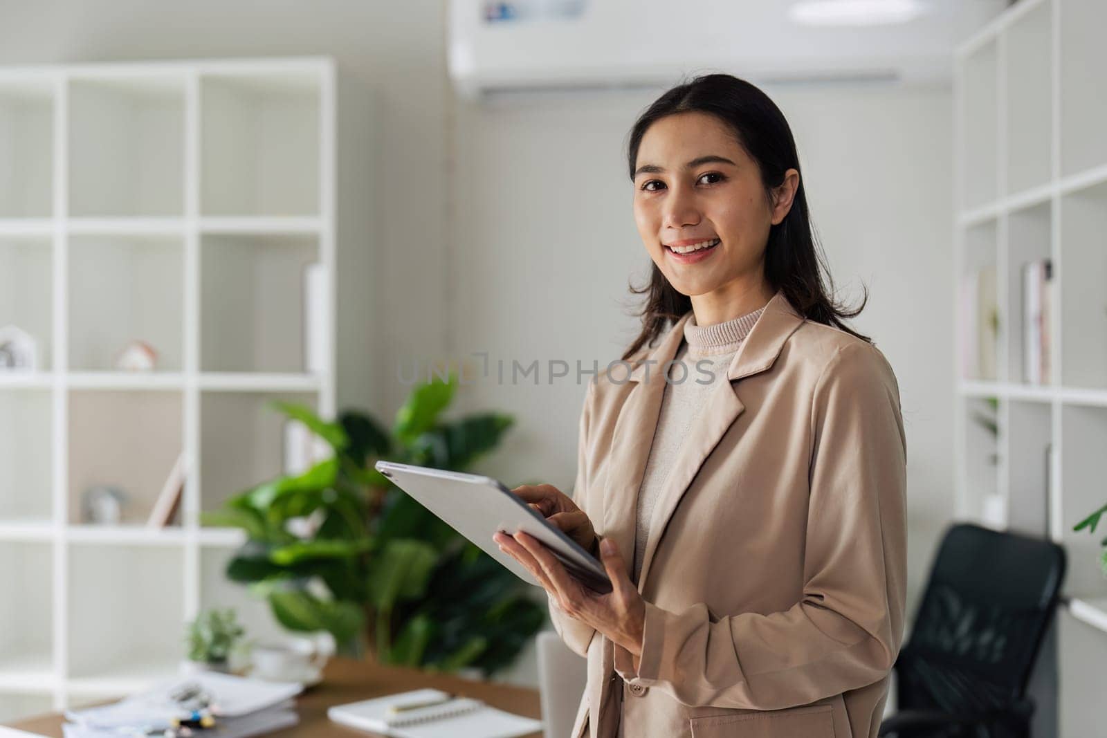 Confident Businesswoman using digital tablet while standing in front of desk.