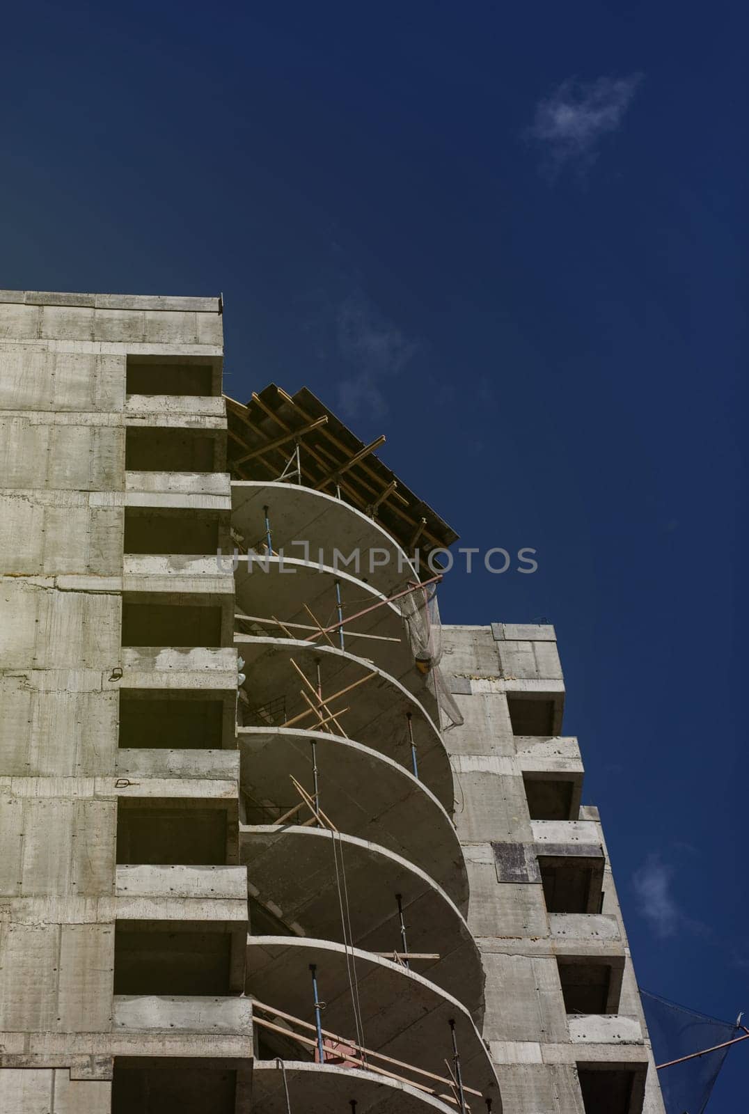unfinished high-rise building on a construction site. The new building is being built against a blue sky. Mortgage