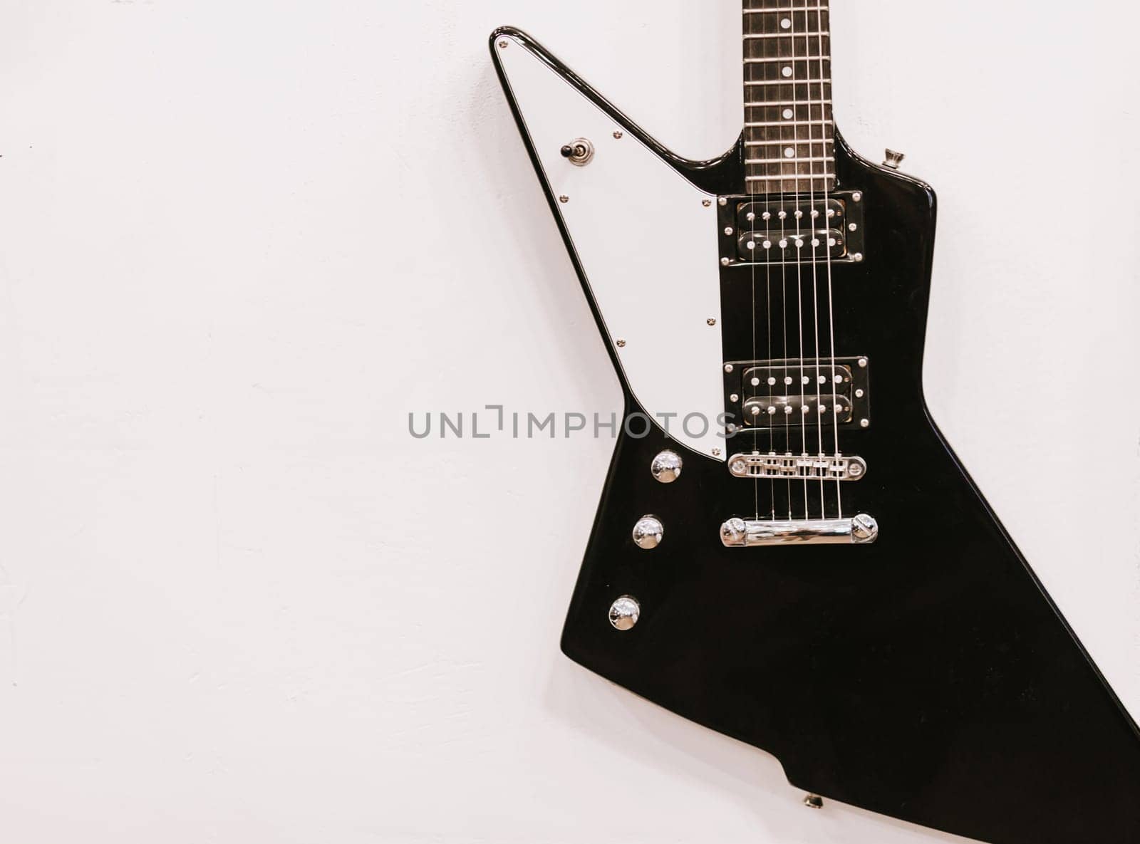 Black and white guitar hanging on the wall. Copy space