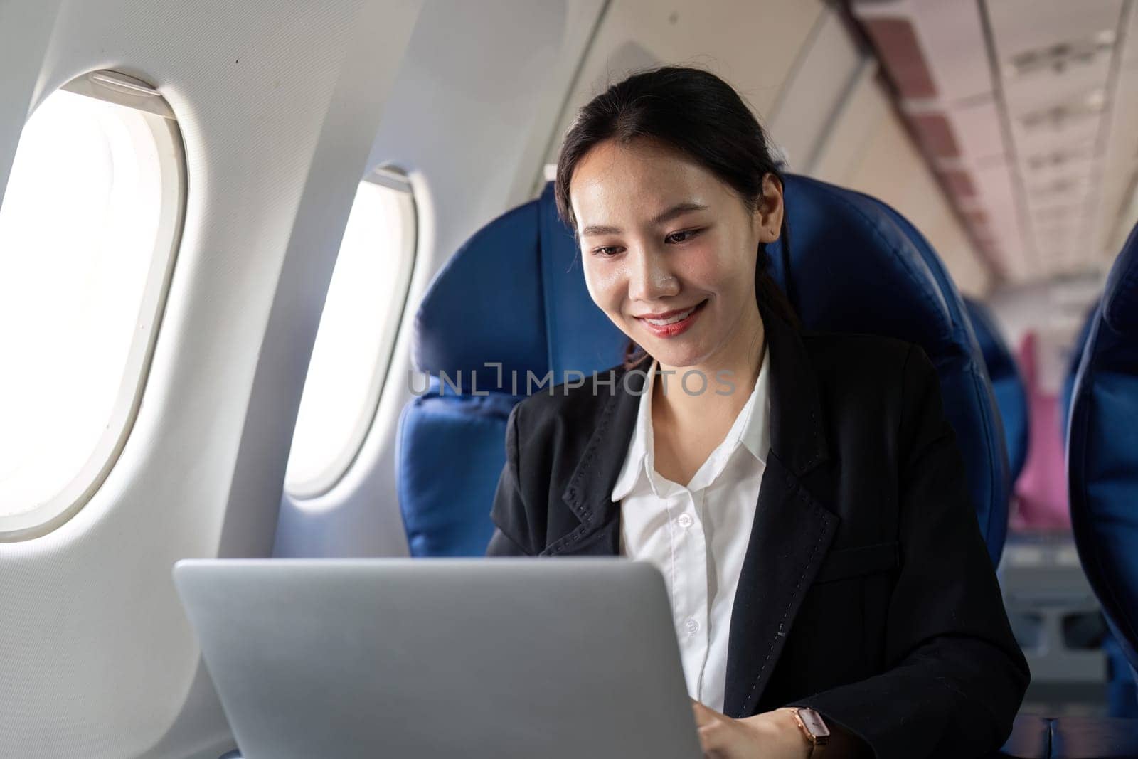 Asian young woman using laptop at first class on airplane during flight, Traveling and Business concept.