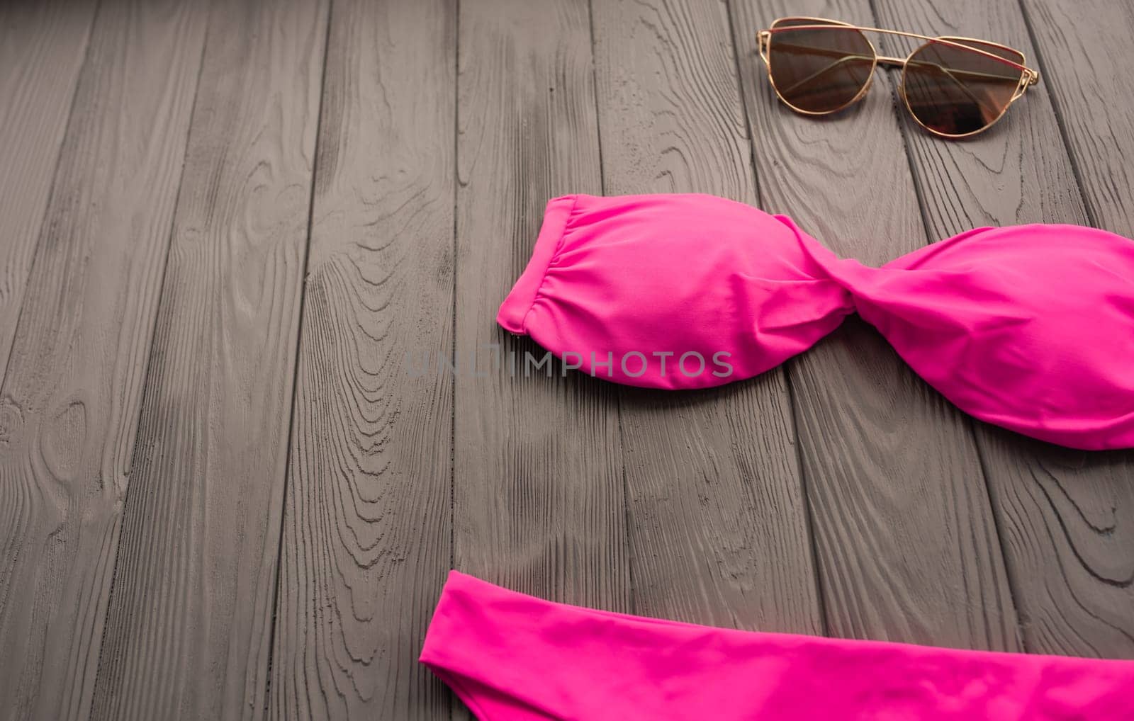 woman trending two-piece swimsuit beach pink swimwear fashion sunglasses. Summer background template mockup copy free space colorful composition sample text. Top view above grey wooden background.