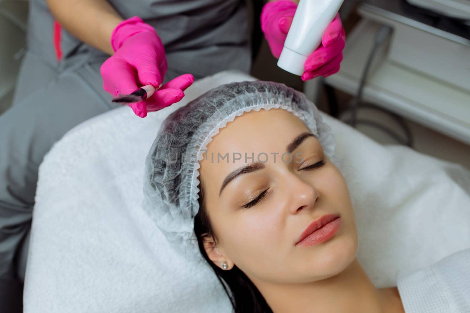 Cosmetician Applying Facial Mask On Face Of Woman.