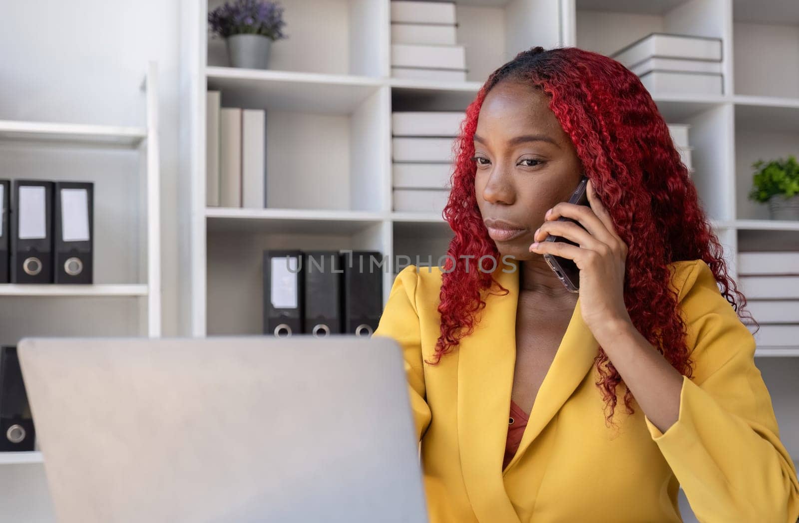 African American businesswoman talking on the phone while working in the office with stress.