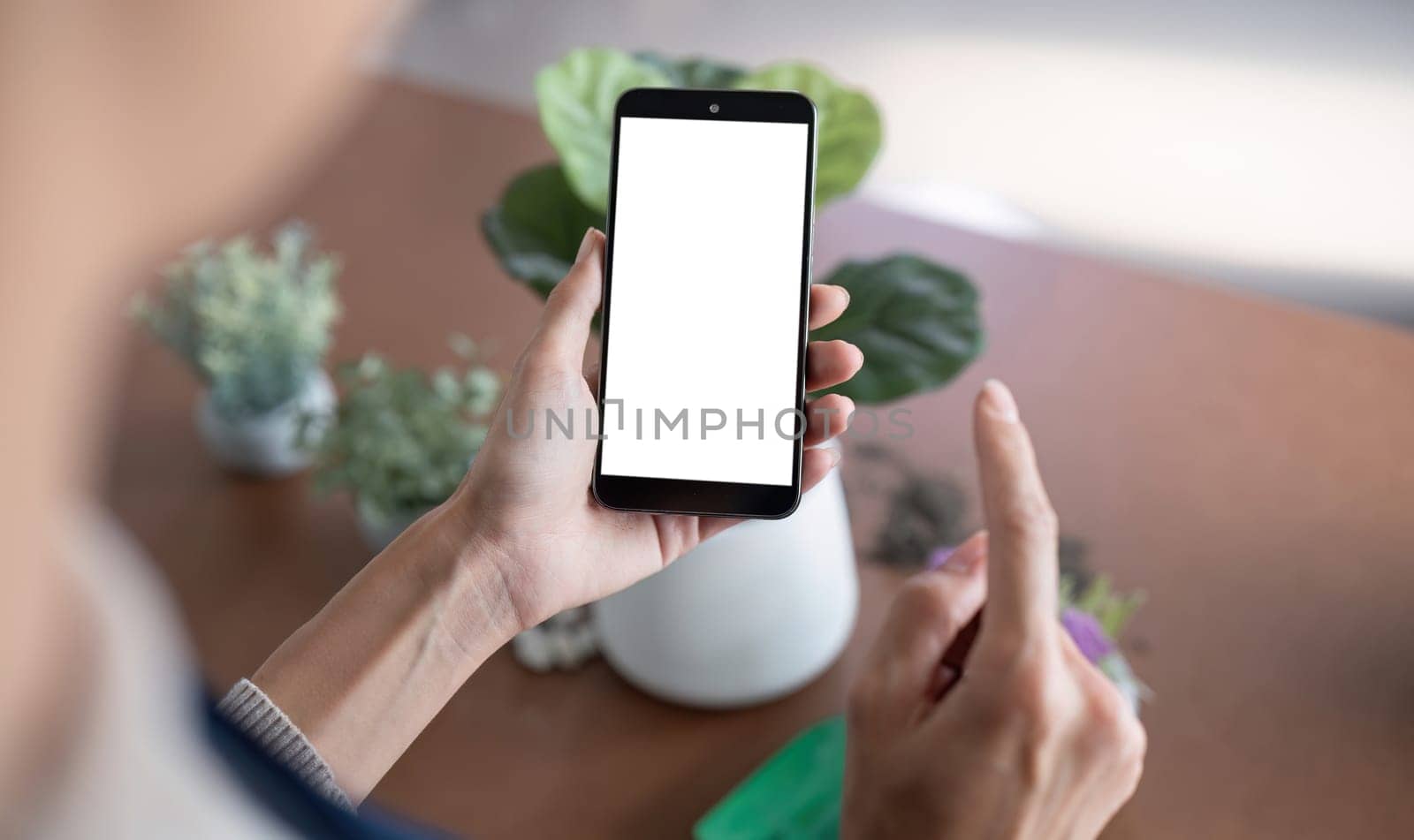 Simulated image of a blank white screen mobile phone Woman using mobile phone on table at home by wichayada