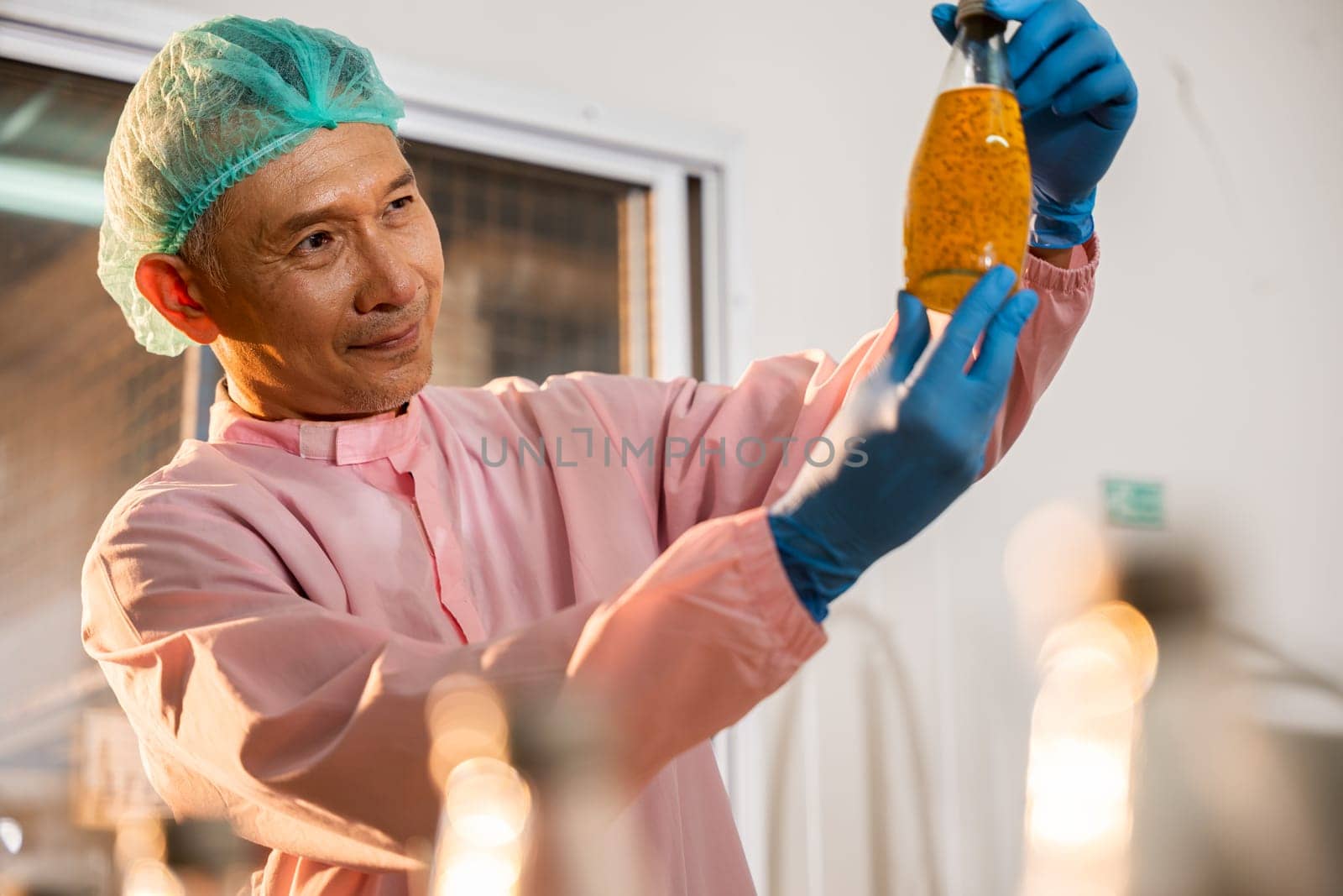 A colleague in a beverage factory inspects Basil seed products on the conveyor belt. His dedication as an inspector contributes to maintaining the industry's high manufacturing and quality standards.