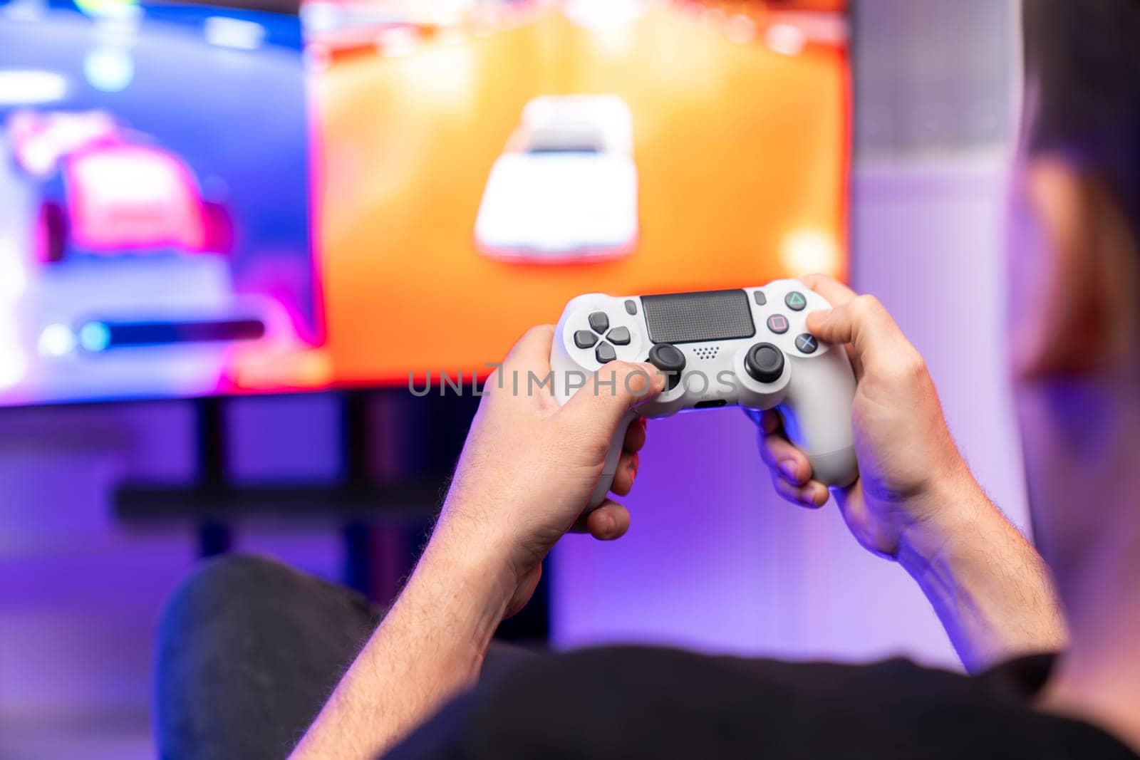 Close up of photo of holding joystick with two hands by gaming streamer playing car racing competition of video game on blurred screen. Concept of lifestyles gamer on weekend with friend. Sellable.