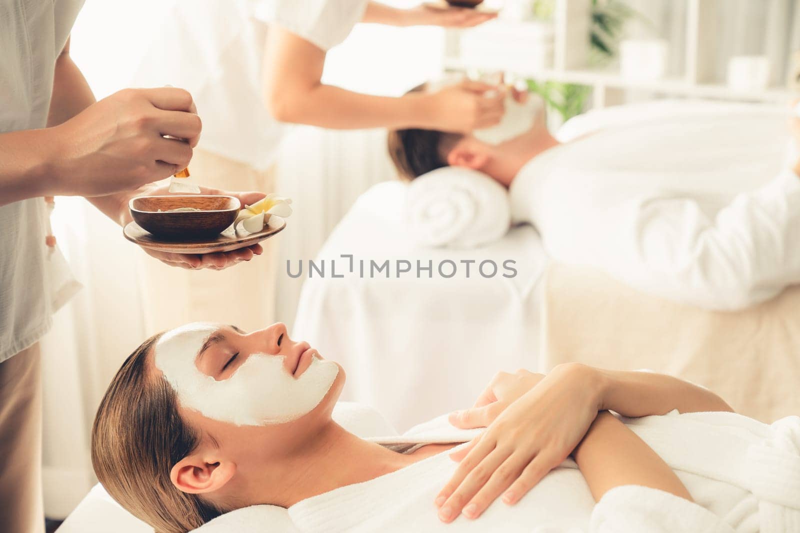 Serene ambiance of spa salon, couple indulges in rejuvenating with luxurious face cream massage with modern daylight. Facial skin treatment and beauty care concept. Quiescent