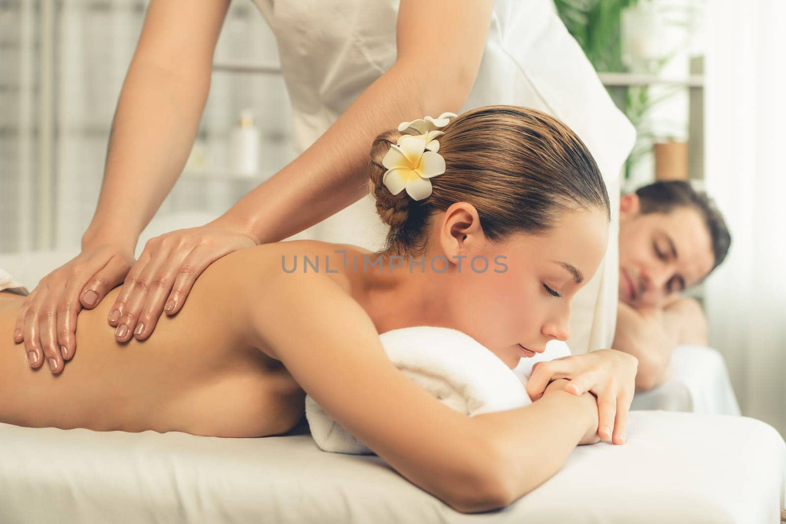 Caucasian couple customer enjoying relaxing anti-stress spa massage and pampering with beauty skin recreation leisure in day light ambient salon spa at luxury resort or hotel. Quiescent