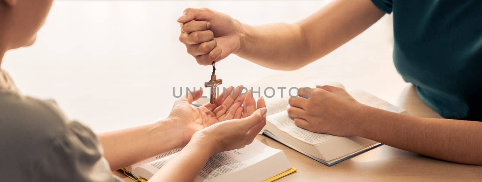 Close-up women prayer deliver wooden cross to young believer. Burgeoning. by biancoblue