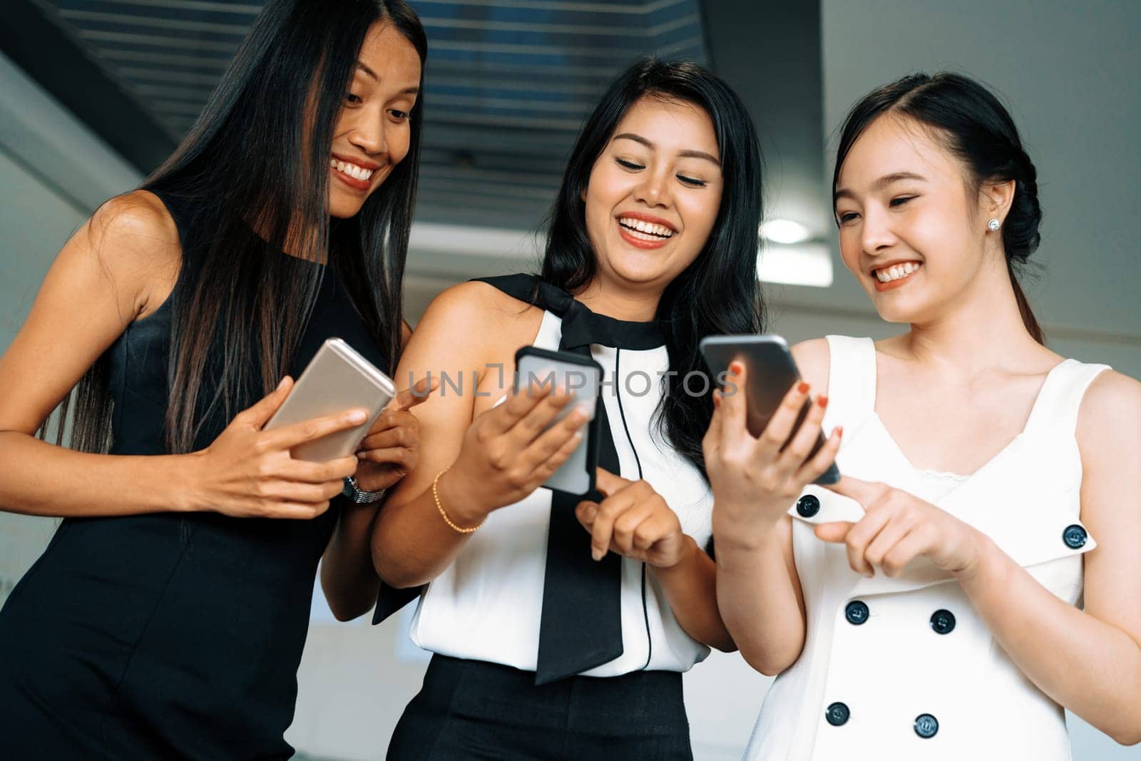 Three women friends having conversation while looking at mobile phone in their hands. Concept of social media, gossip news and online shopping. uds