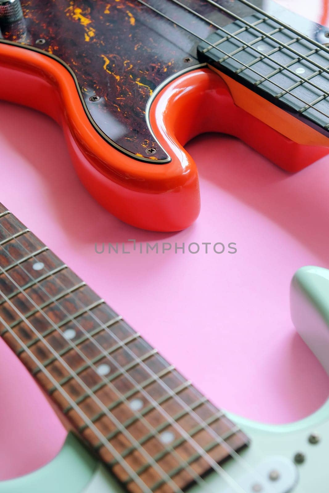Electric guitar and bass guitar on a pink background with copy space.