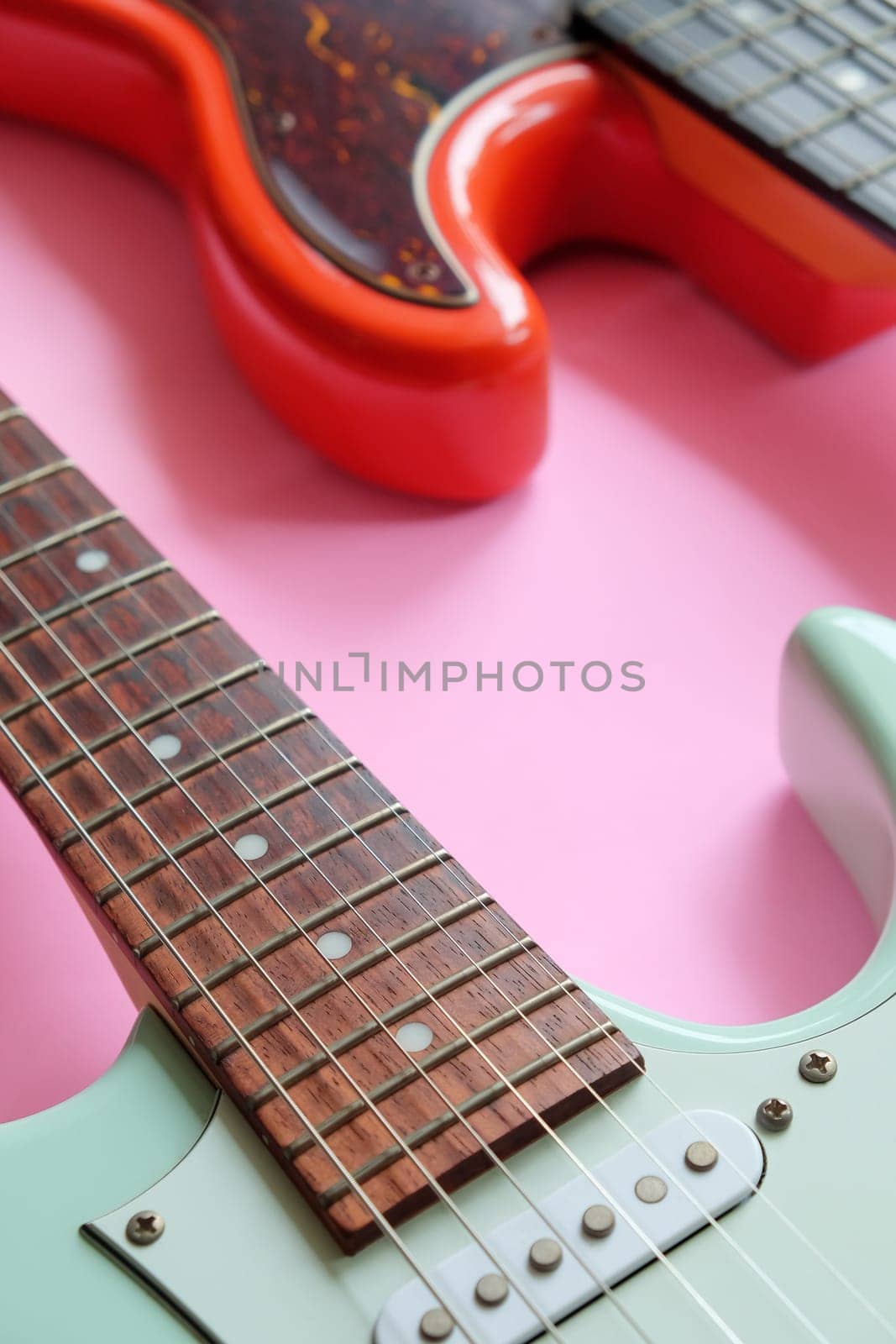 Electric guitar and bass guitar on a pink background with copy space.