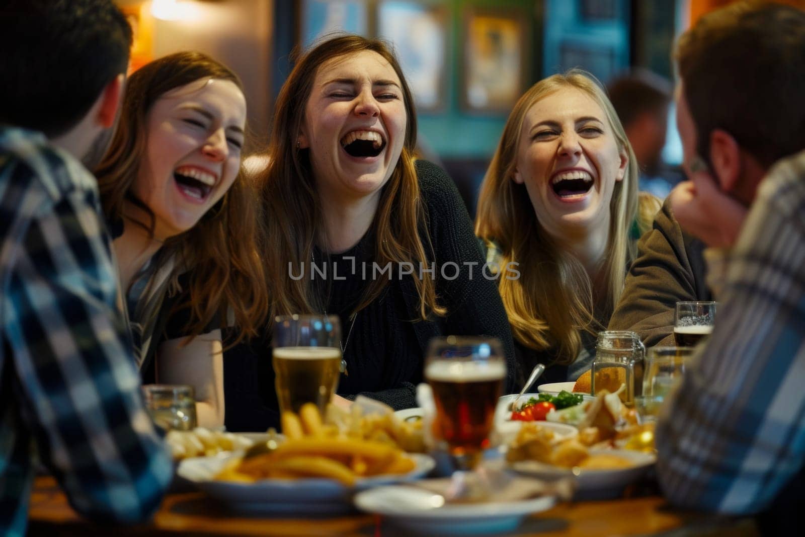 Female friends laughing while enjoying food and drinks with friends.