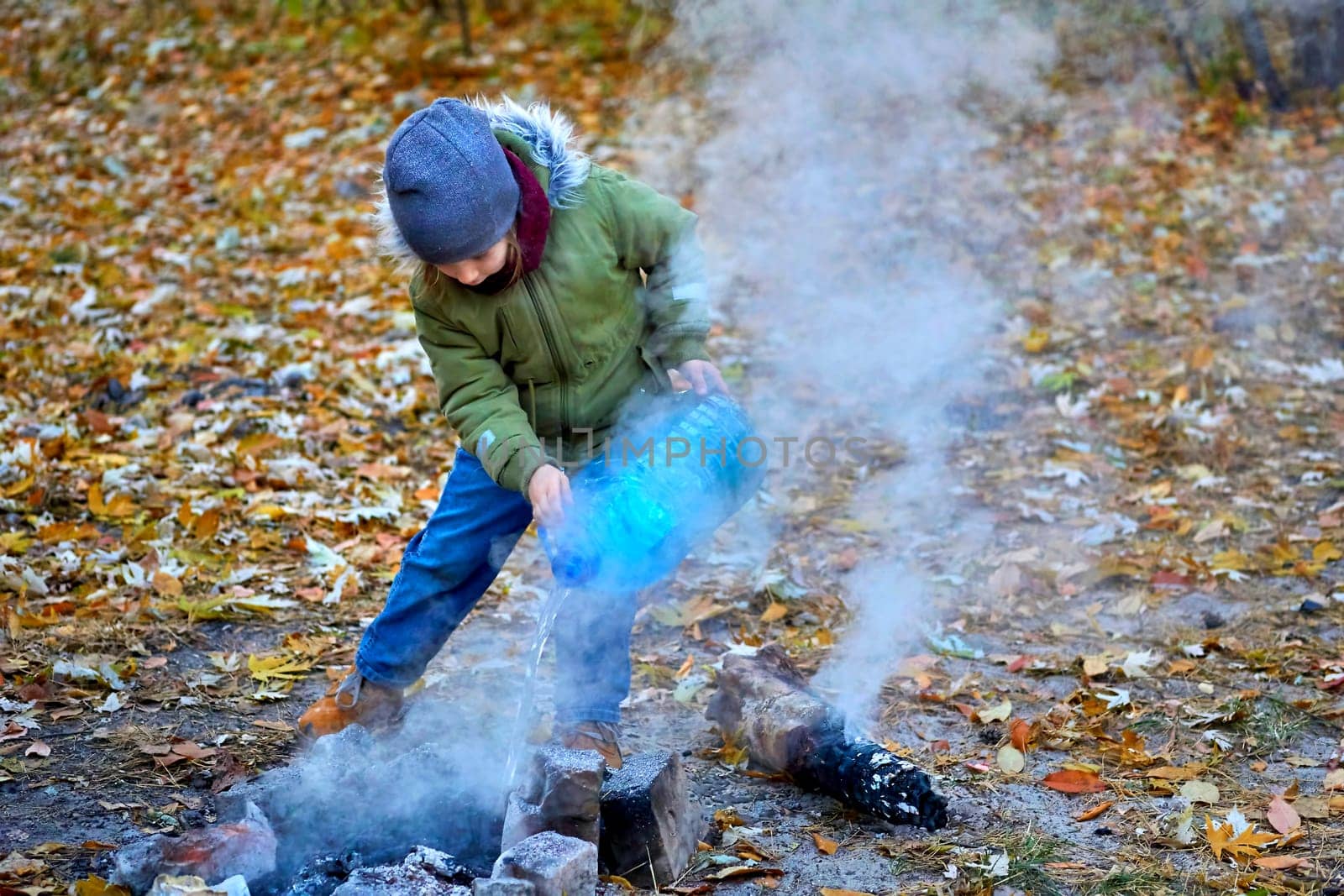 A child puts out a fire after a picnic in the autumn forest by jovani68