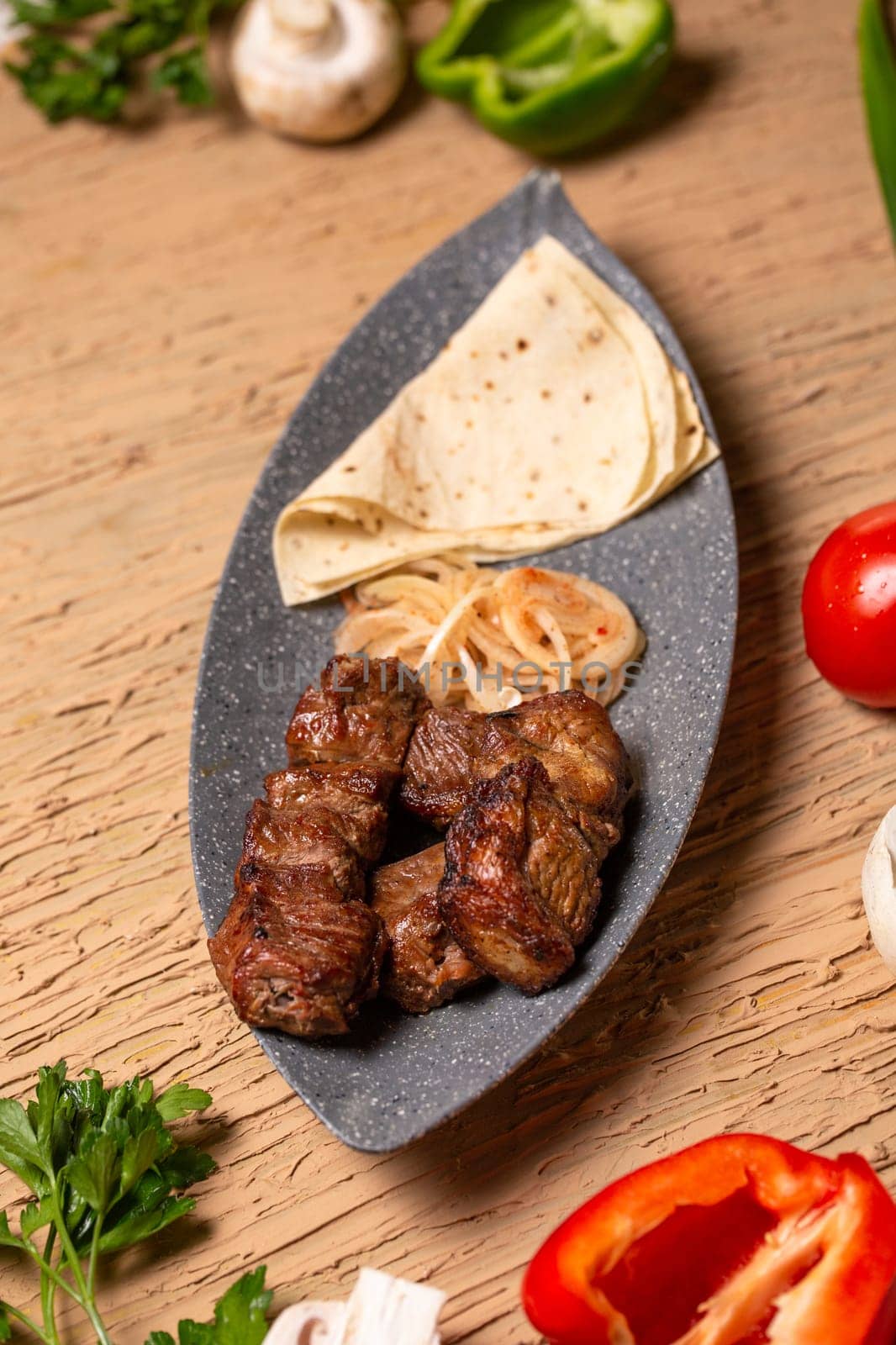 Juicy meat kebab with vegetables and herbs on a wooden table. view from above by Pukhovskiy