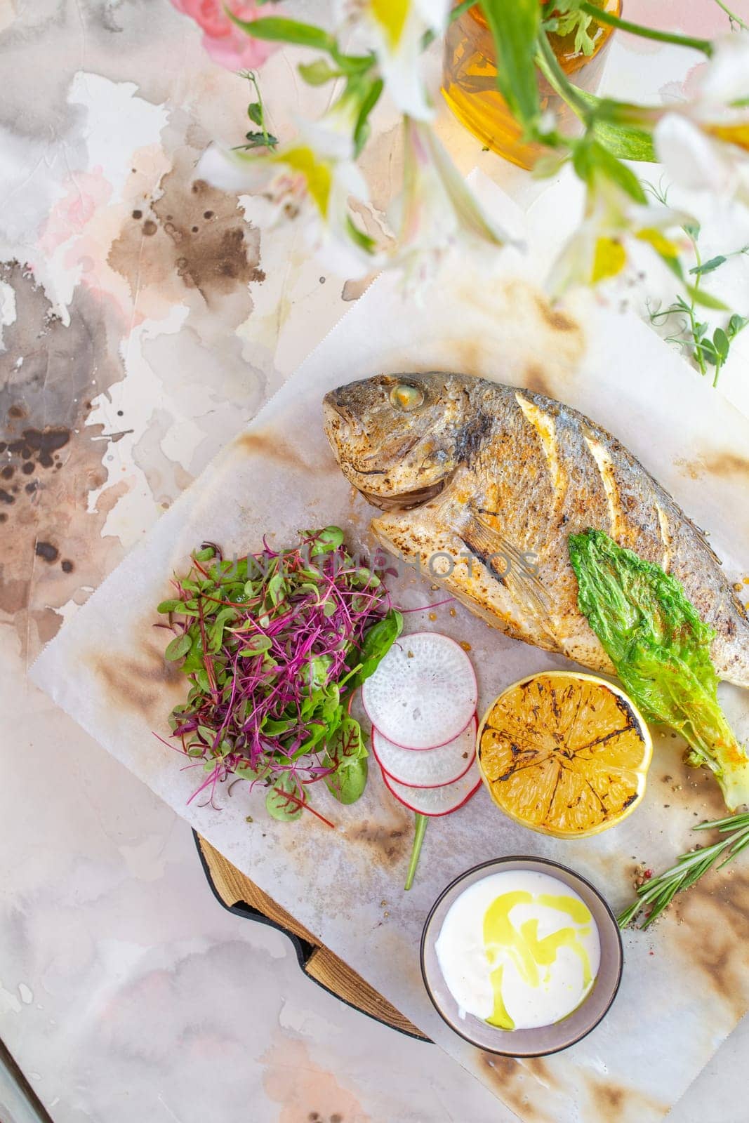 Grilled fish Dorado with lemon and herbs on a white background top view. by Pukhovskiy