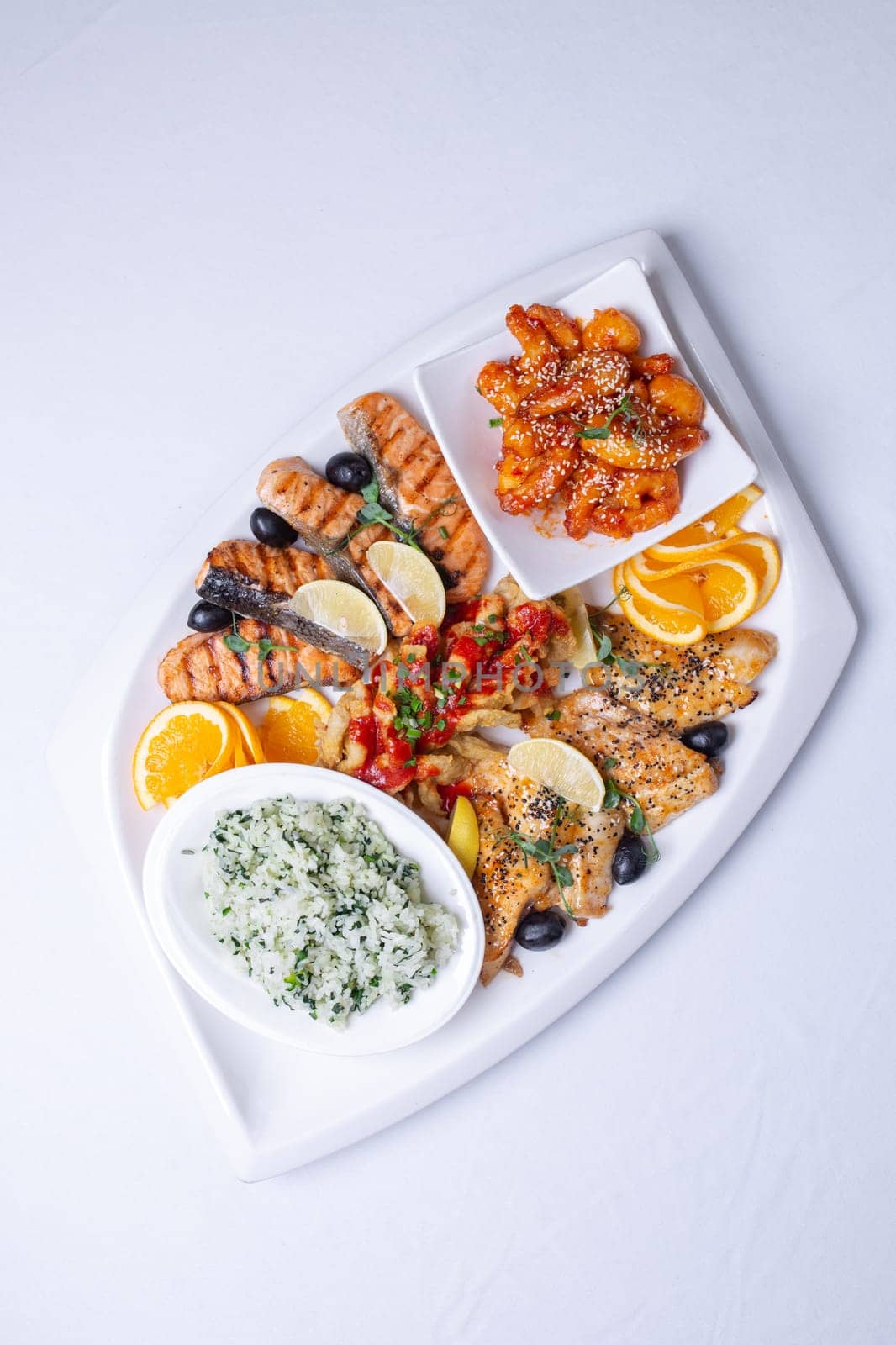 top view seafood mixture on a white grill. Delicious grilled fish, shrimp in sauce and salmon on the table by Pukhovskiy