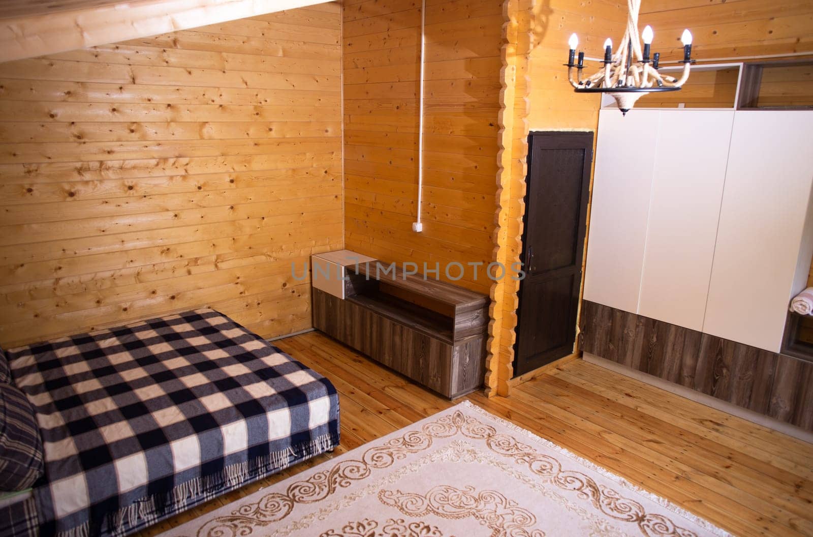 The bedroom is decorated with warm wood paneling and a soft, inviting bed. A beautiful chandelier provides soft lighting.