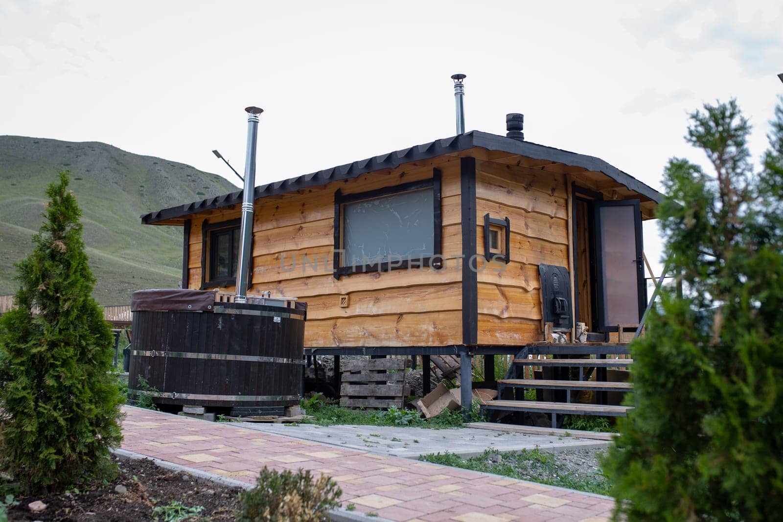 Wooden hot tub on the terrace of a house with a mountain landscape in the background. Relaxation and tranquility in nature.