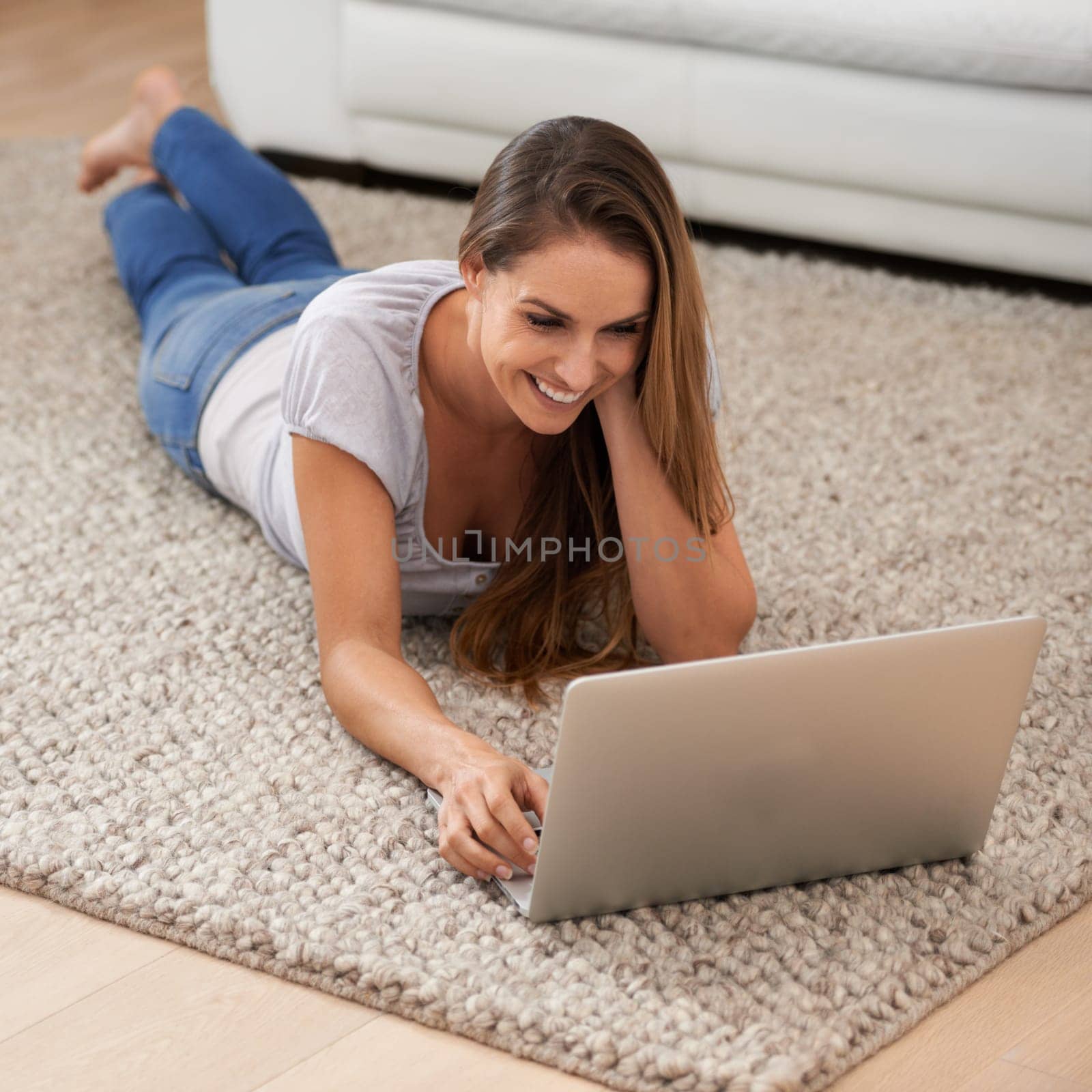 Woman, happy and laptop on floor with reading for blogging, communication and email on mat in living room of home. Person, smile and technology on ground with relax, streaming show and watching video by YuriArcurs