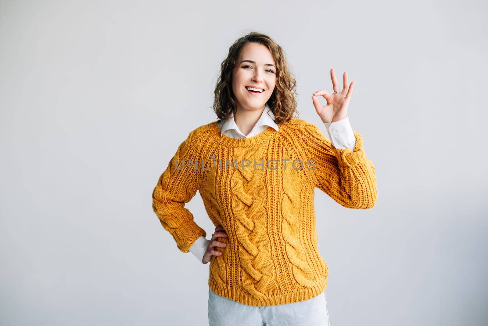 Confident Woman Gesturing OK. Smiling Lady Recommends Product with Hand Sign - Advertising Concept - Isolated on White Background - Positive Gesture for Promotion or Service Endorsement