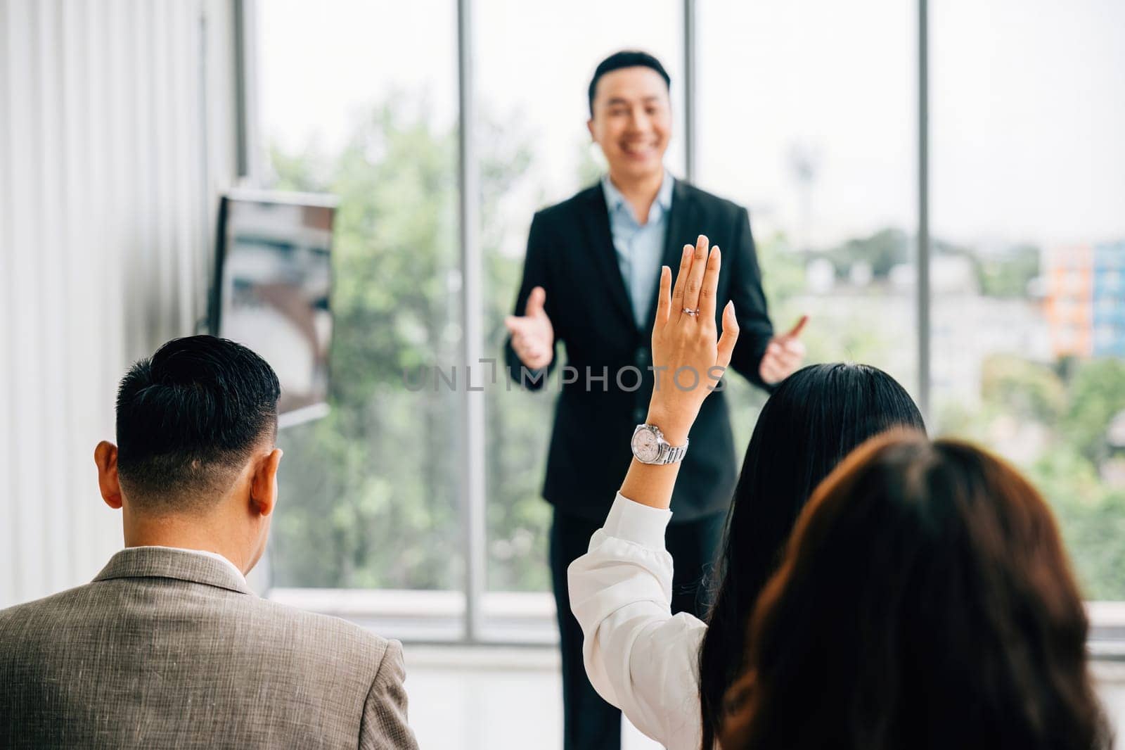 Businesspeople in seminar meeting room raise their hands to engage the speaker, reflecting active audience participation and a strong sense of teamwork. It all about the question and answer concept. by Sorapop