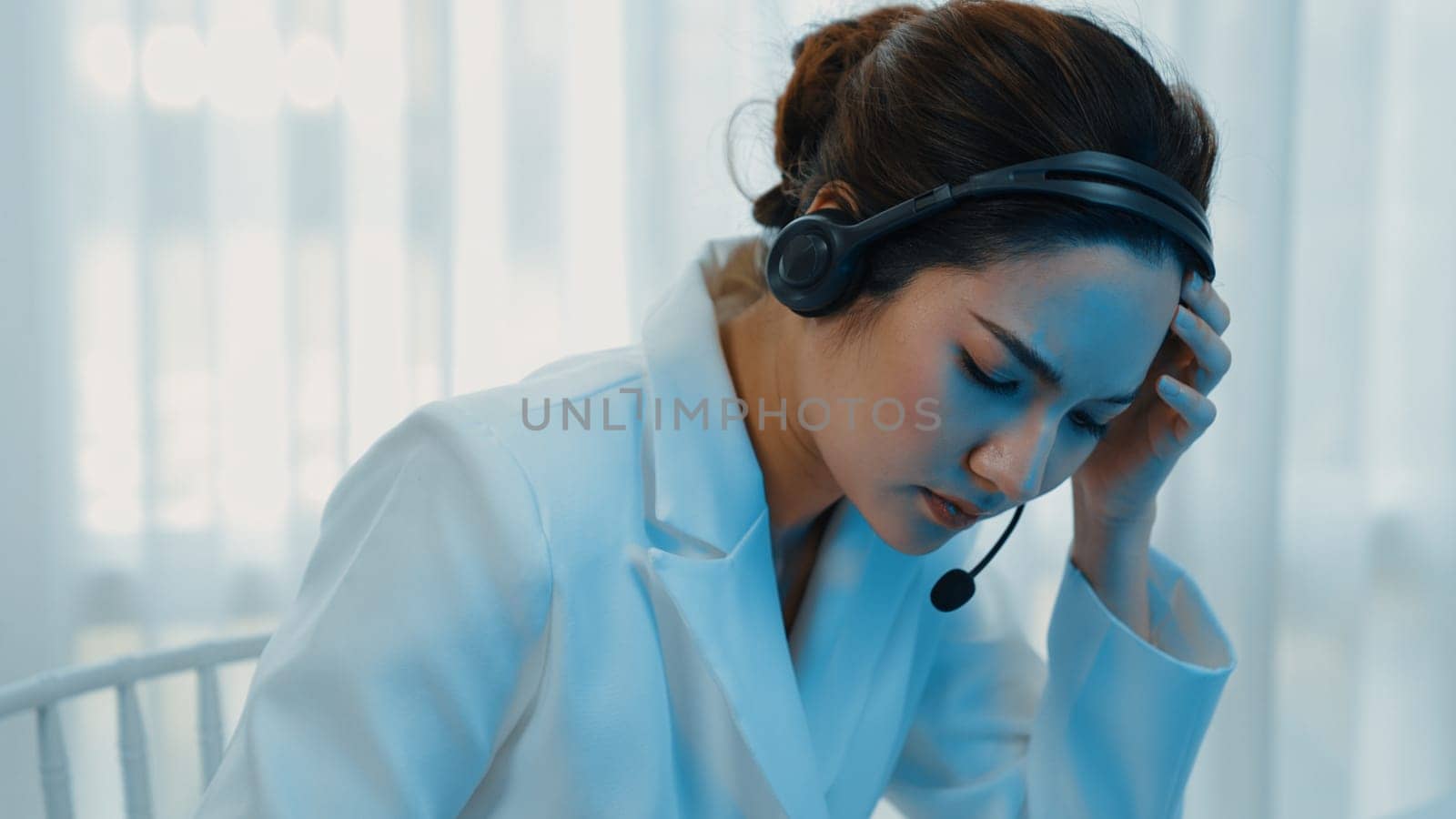 Businesswoman wearing headset working in office to support remote customer or colleague. Frustrated and tired call center customer support agent facing problem on providing vivancy service