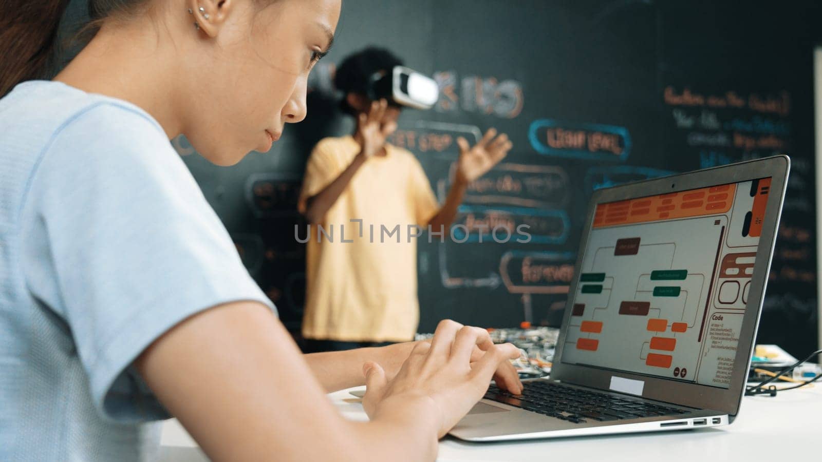 Closeup of school girl hand coding program while african student using VR interact with metaworld. Smart boy wearing virtual reality glasses and playing video games at innovative class. Edification.