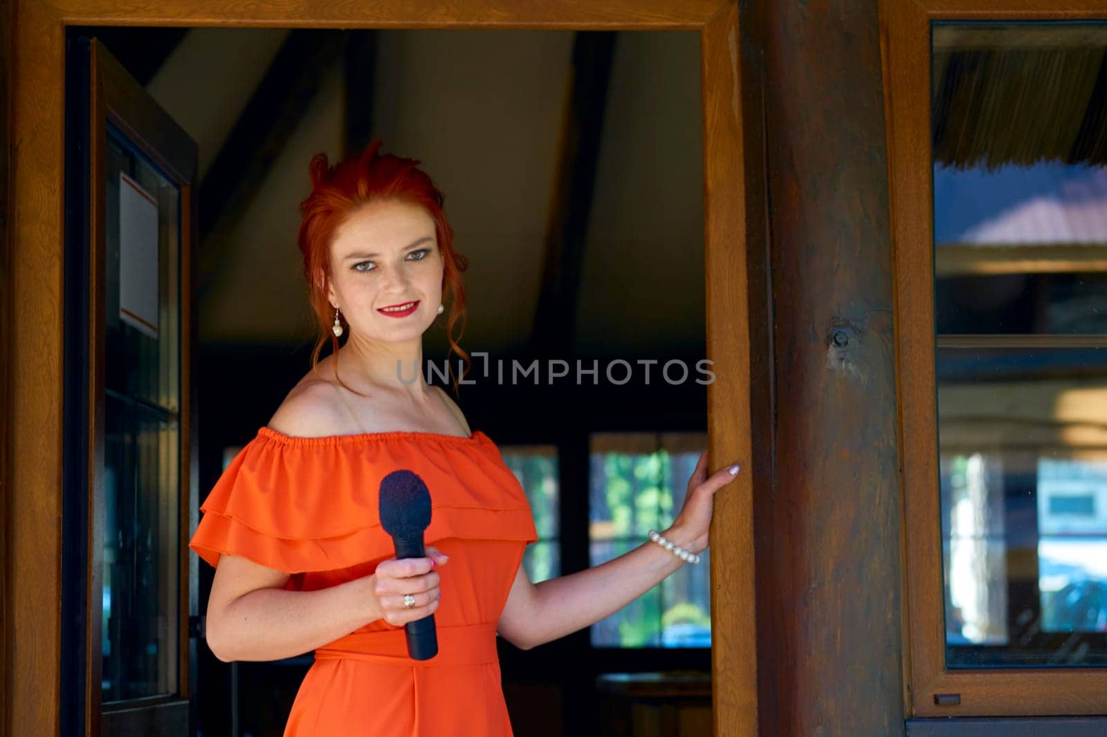 The host of the wedding ceremony. Young woman in a red dress with a microphone by jovani68