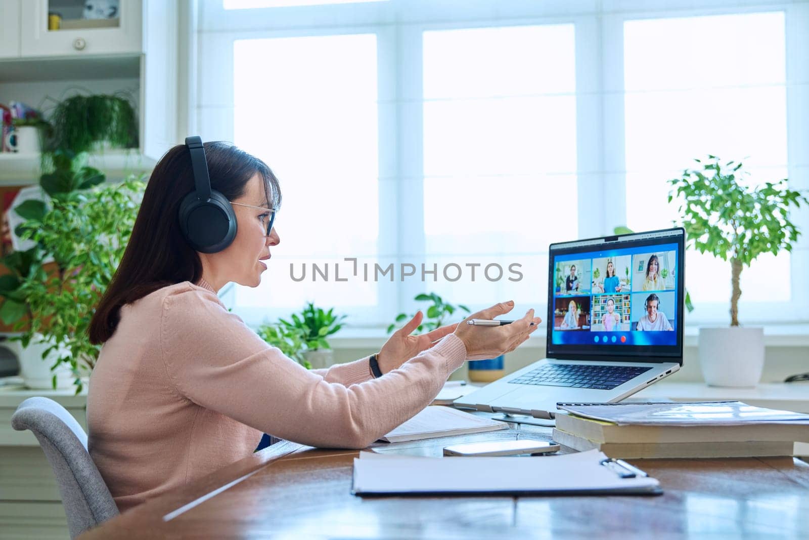 Woman teacher in headphones teaching online, high school students on laptop computer screen, video conference. Remote meeting, consultation, e lesson, training, education, technology concept