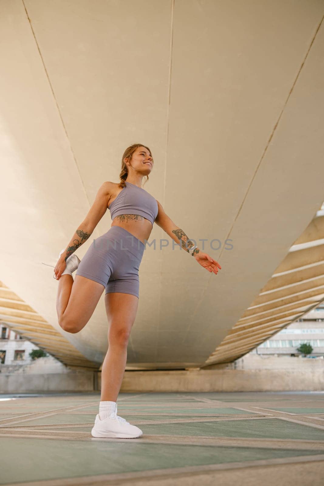 Athletic woman in sportswear stretching legs before doing workout outside in morning by Yaroslav_astakhov