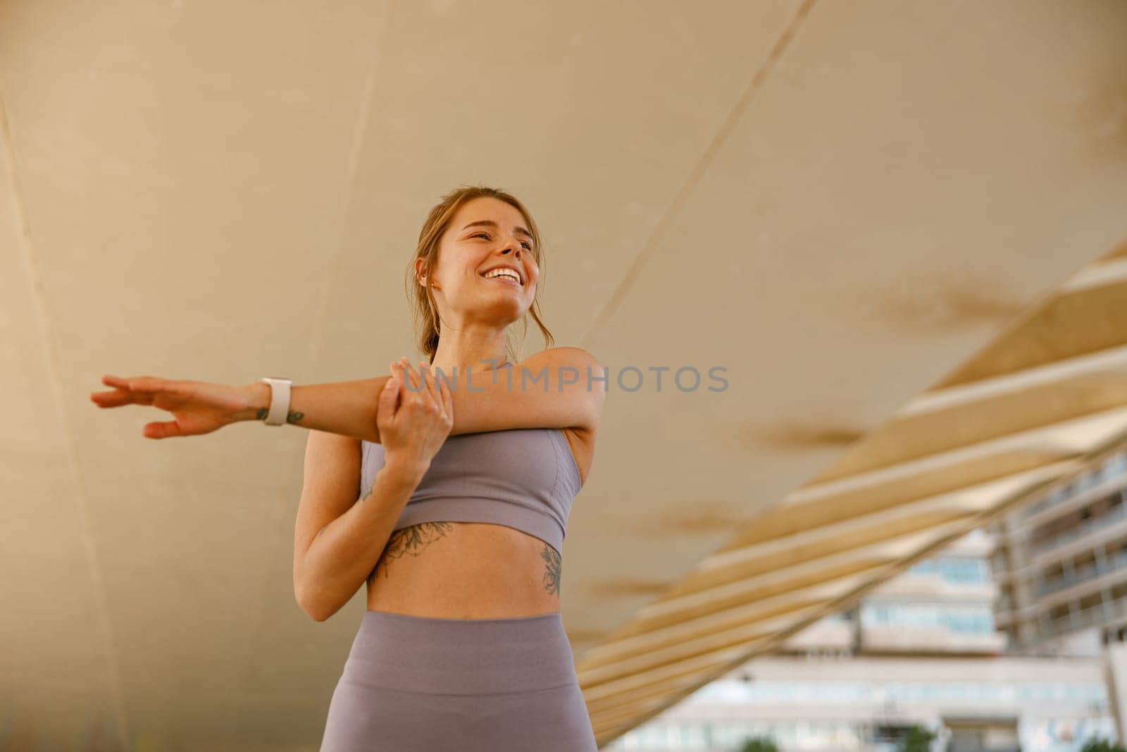 Smiling sportswoman in tracksuit stretching outdoor and preparing to jogging. Healthy life concept