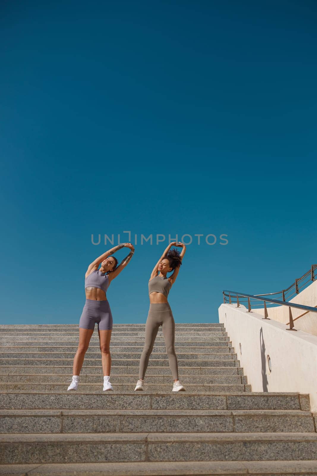 Young sportswomen in tracksuit are stretching outdoor and preparing to jogging. Healthy life concept by Yaroslav_astakhov