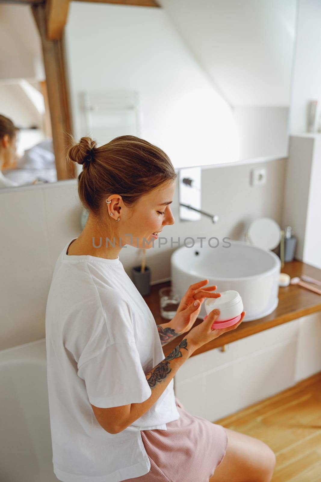 Young woman holding jar with skincare cream in hands. Home beauty routine by Yaroslav_astakhov