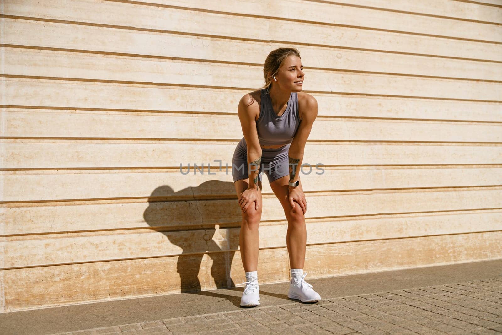 Female athlete in sportswear have a rest after morning jogging outside and looks away by Yaroslav_astakhov