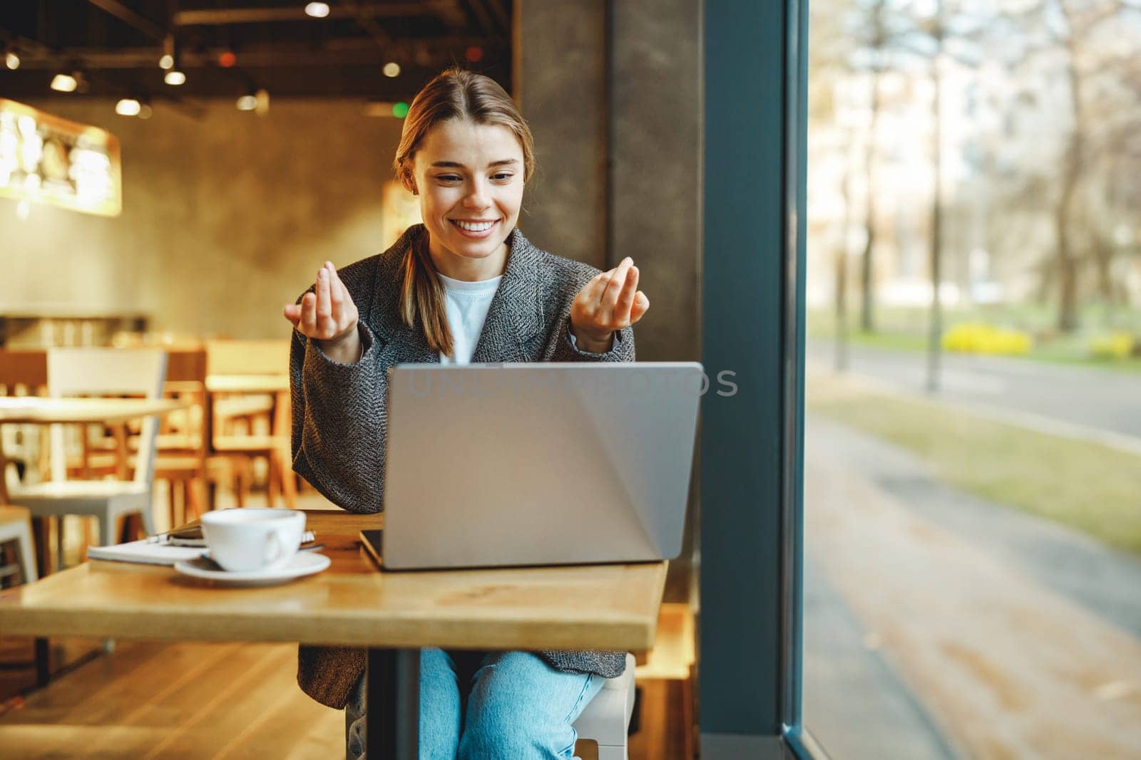 Smiling businesswoman talking via video call with client while sitting in cafe