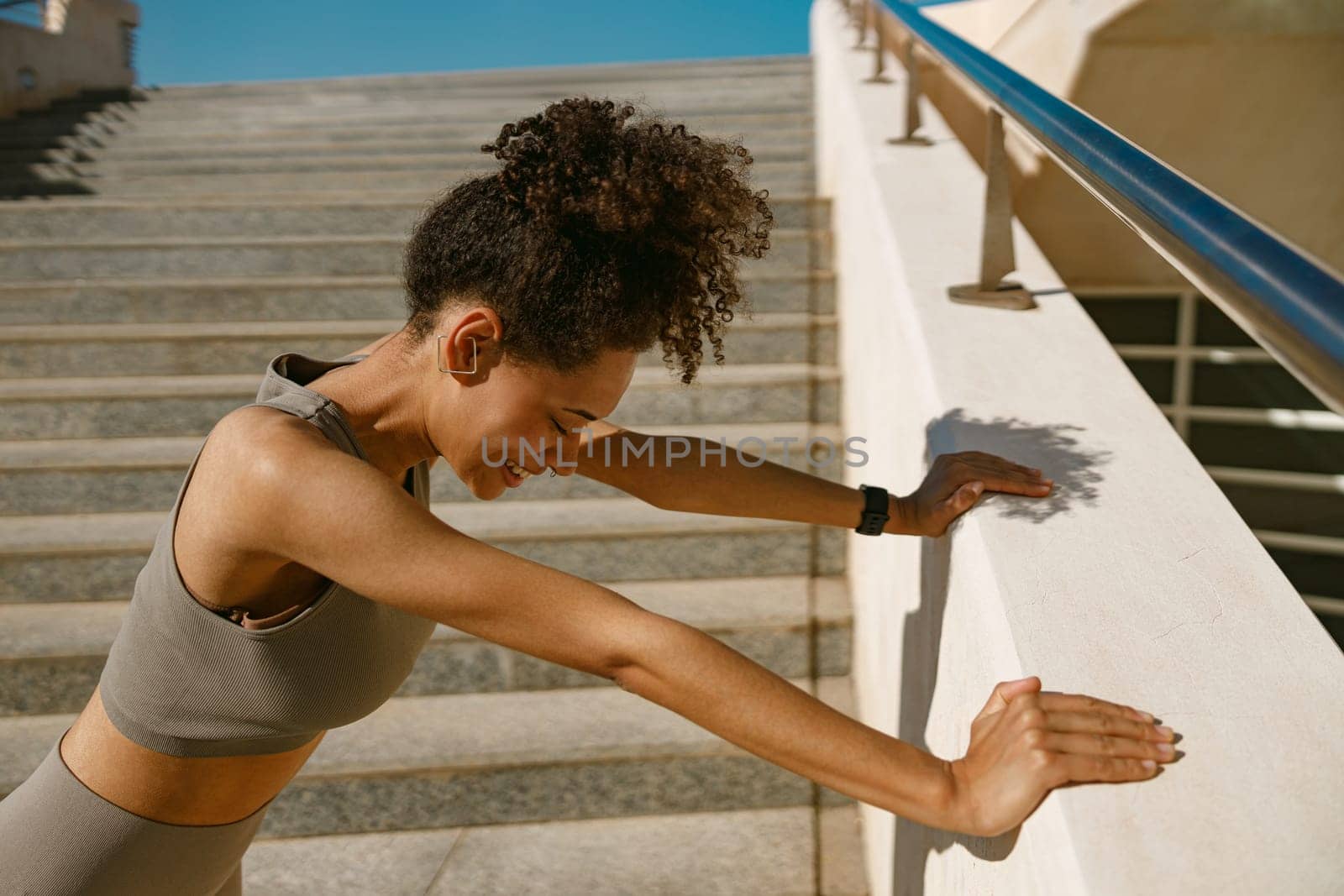 Fit woman in sportswear have a rest after workout outside standing on stairs background