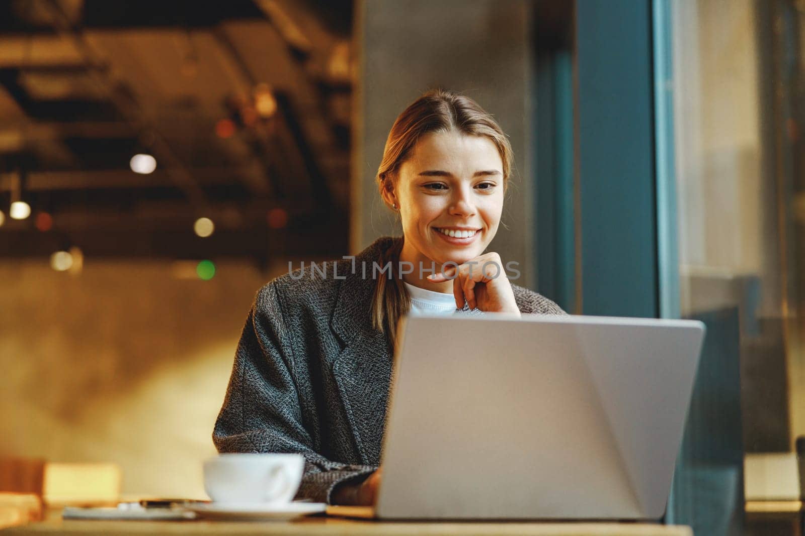 Smiling business woman working on laptop while sitting in cozy cafe by Yaroslav_astakhov