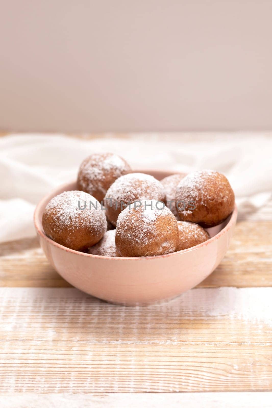 Paczki Or Zeppole In Pink Bowl With Powdered Sugar On Wooden Table. Fat Thursday Carnival or Tlusty Czwartek, Christian tradition Of Eating Doughnut, Delicious Donuts. Vertical Plane. by netatsi