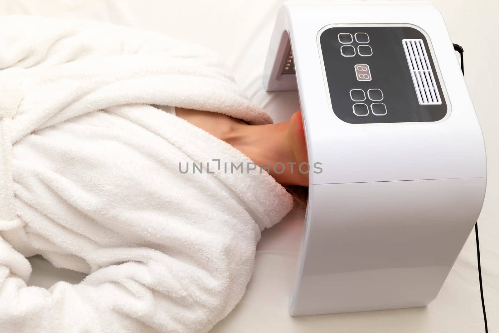 Top View Home Skin Care Procedure. Cosmetic Led Light Face Mask. Woman Lying Under Facial Regenerative Treatment Mask On Bed In Bedroom. Acne, Spot Cure. Beauty Photon Therapy. Horizontal Plane.