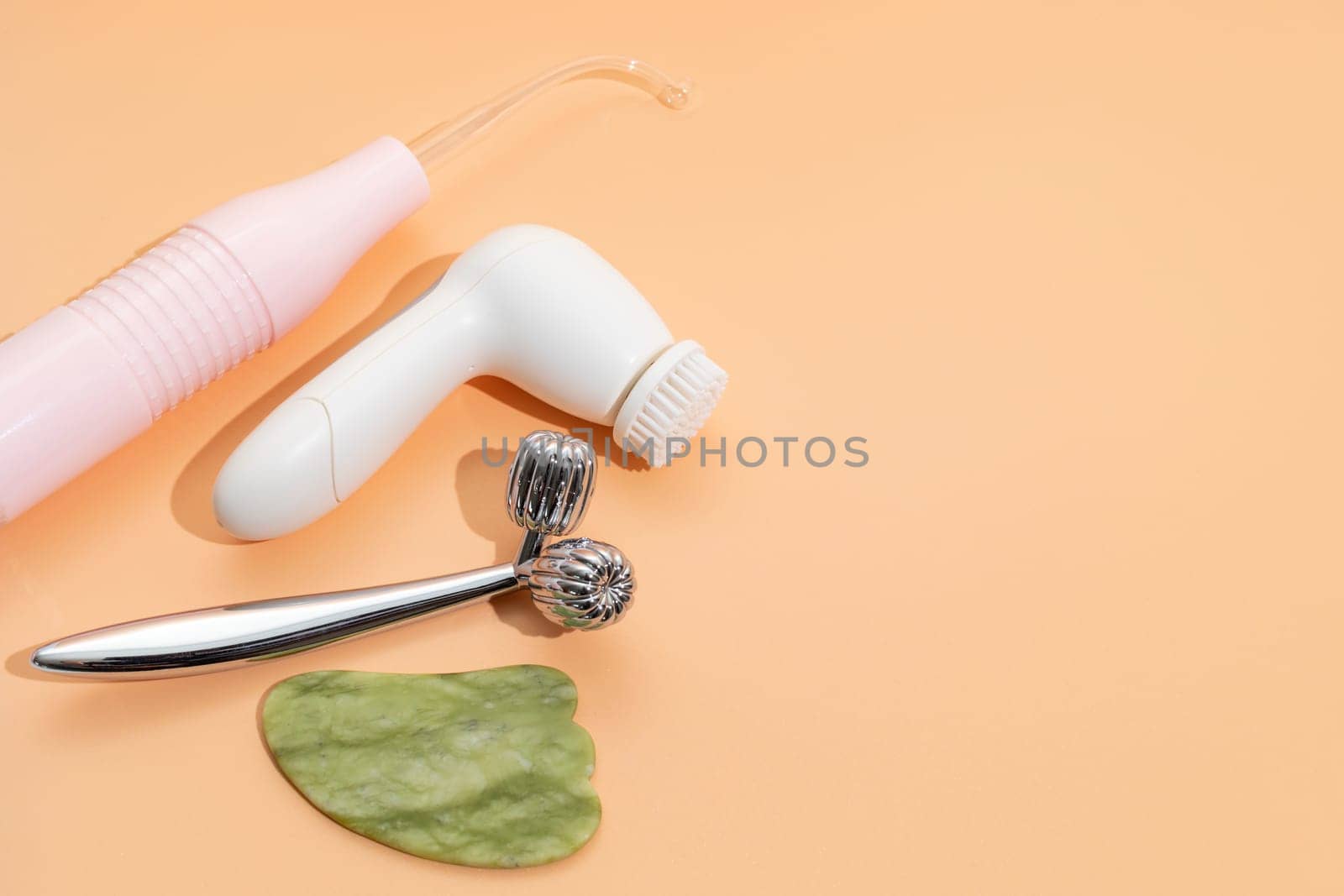Flatly Mockup Skin Care Products. Facial Tool Gua Sha, Darsonval Skin Beauty Device, Sculpt Facial Roller, Anti-Aging, Facial Cleansing Brush on Beige Background. Copy Space For Text. Horizontal Plane by netatsi
