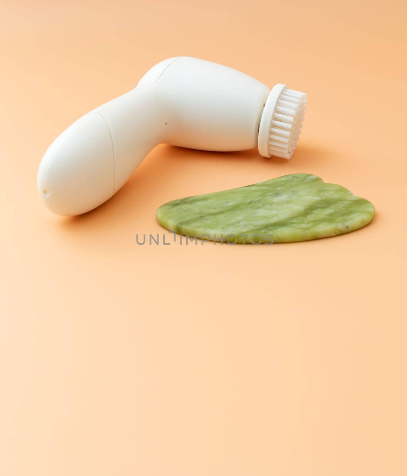Flatly Mockup Skin Care Products. Facial Tool Gua Sha, Anti-Aging, Facial Cleansing Brush on Beige Background. Skin Beauty Device, Copy Space For Text. Vertical