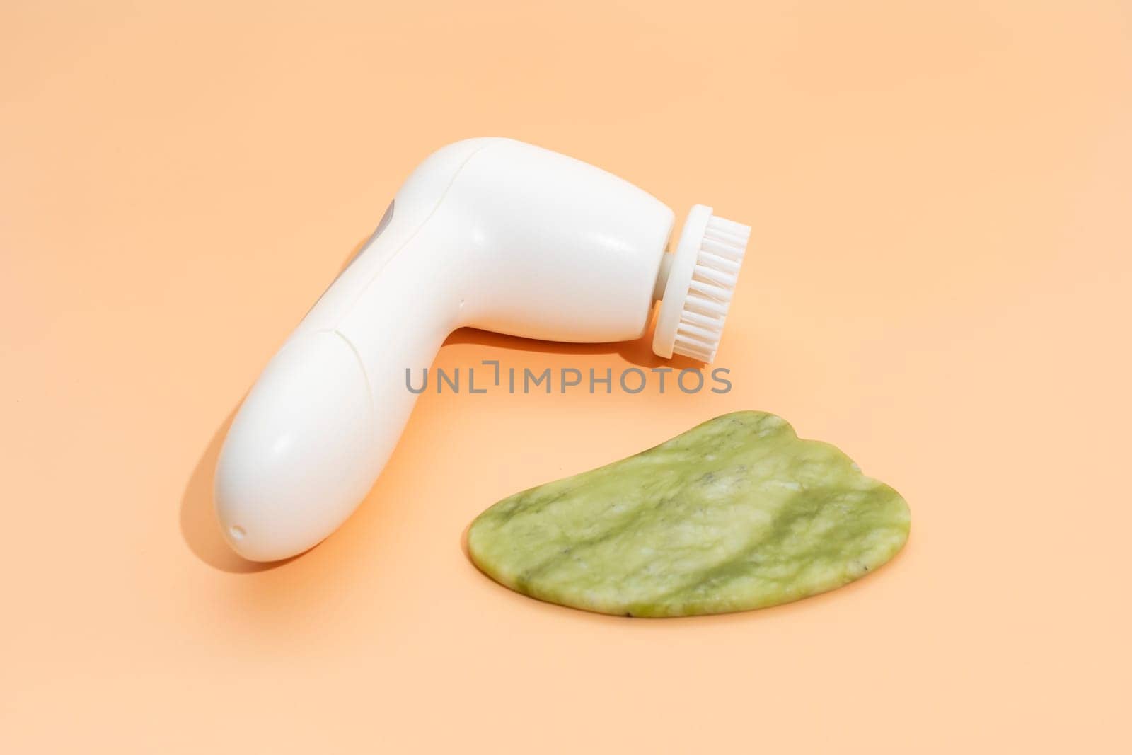 Closeup Skin Care Products. Facial Tool Gua Sha, Anti-Aging, Facial Cleansing Brush on Beige Background. Skin Beauty Device, Horizontal Plane. Nobody. by netatsi