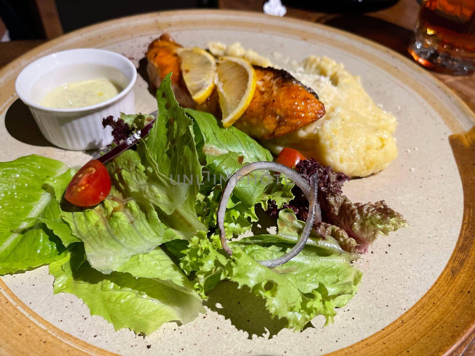 smoked grilled salmon fish served with salad and mash potatoes with lemons on top, served in plate perfect meal